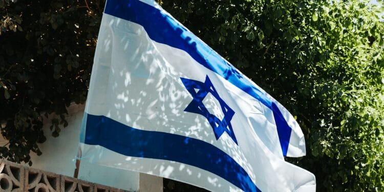 a flag flying in the wind with trees in the background
