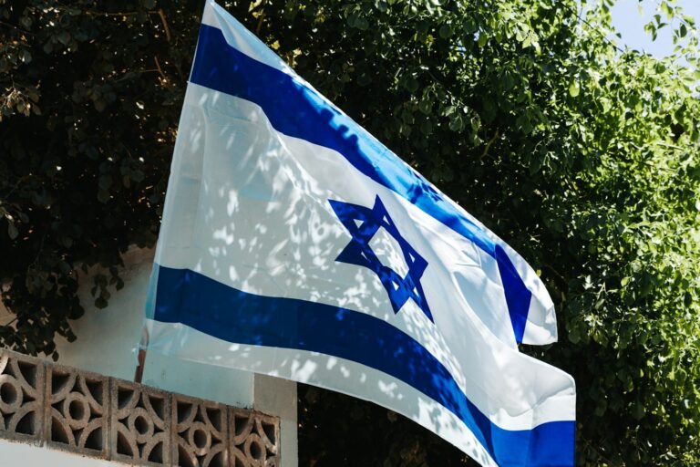 a flag flying in the wind with trees in the background