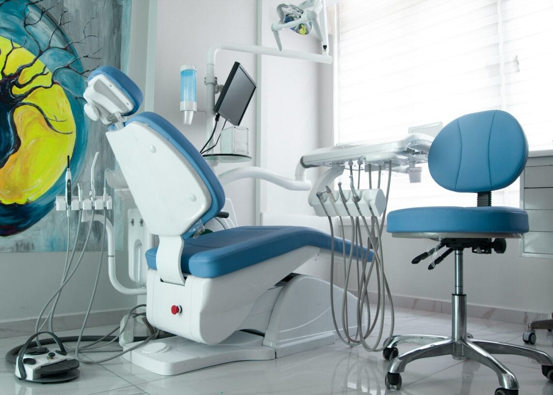 a dentist chair in a room with a painting on the wall