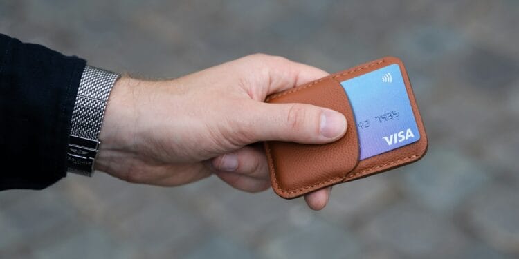 a hand holding a wallet with a credit card in it