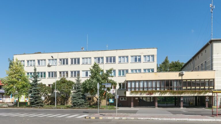 Budynek Urzędu Miasta i Gminy Bystrzyca Kłodzka przy ulicy, za przejściem dla pieszych, w słoneczny dzień.