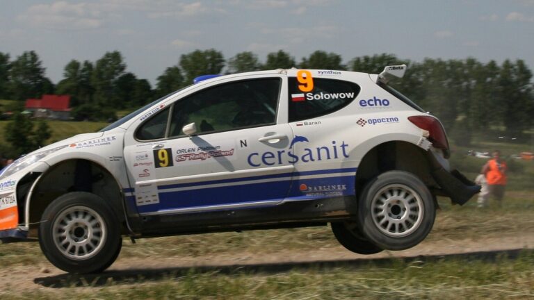 Rajdowy samochód Cersanit Rally Team z numerem 9 i nazwiskiem Sołowow w locie nad szutrową drogą