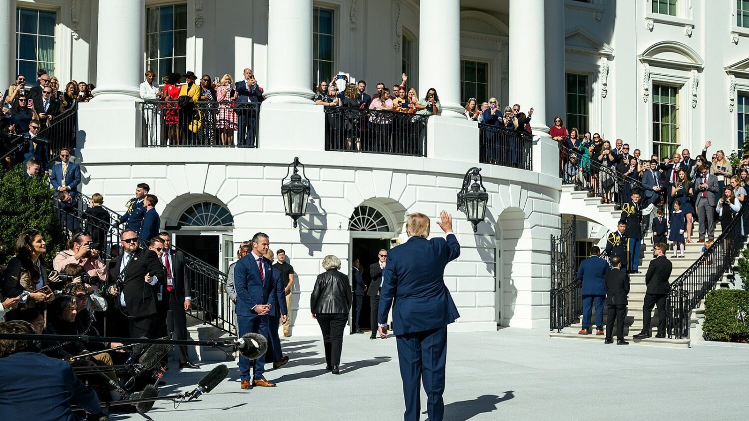 Donald Trump na trawniku w Białym Domu, machający do zgromadzonych ludzi
