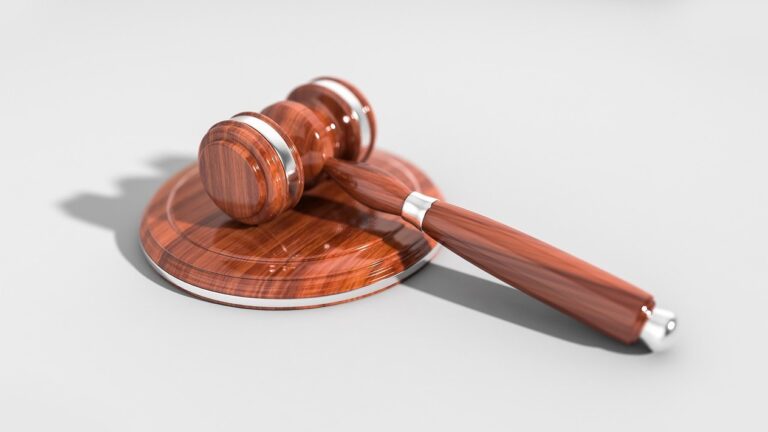 Drewniany młotek sędziowski leżący na podstawce, symbol wyroku sądowego.