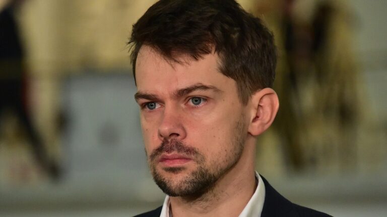Michał Kołodziejczak w ciemnej marynarce przed mikrofonami mediów; archiwalne zdjęcie z 2023 roku, nie z Łodzi.