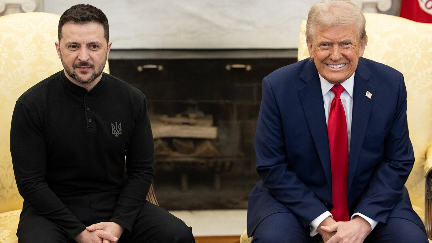Donald Trump i Wołodymyr Zełenski siedzą obok siebie w Białym Domu. Trump się uśmiecha, Zełenski ubrany jest na czarno.