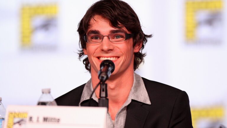 Aktor RJ Mitte, uśmiechnięty, przy mikrofonie podczas panelu na Comic-Con w San Diego w 2012 roku.