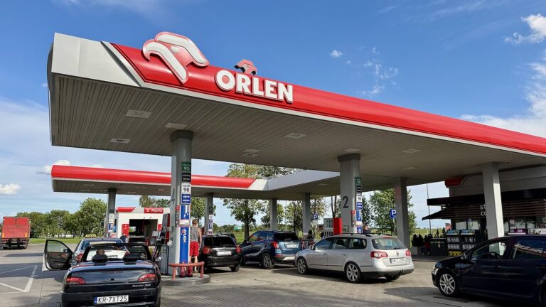 Stacja paliw Orlen w Środzie Śląskiej, samochody tankują na dystrybutorach pod czerwonym zadaszeniem.