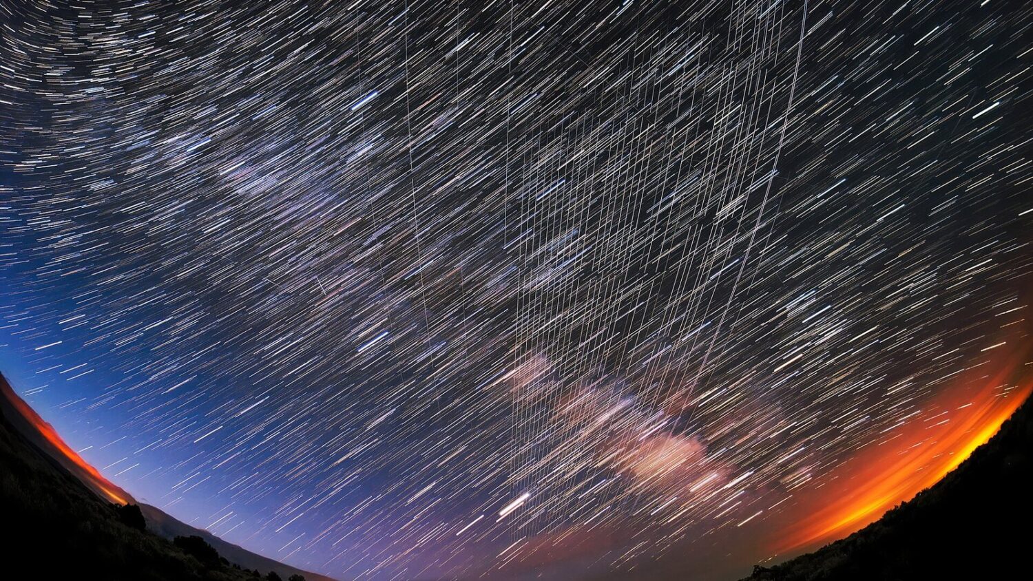 Satelity Starlink przelatują nad nocnym niebem w Nowym Meksyku, widoczne jako jasne smugi na tle gwiazd.
