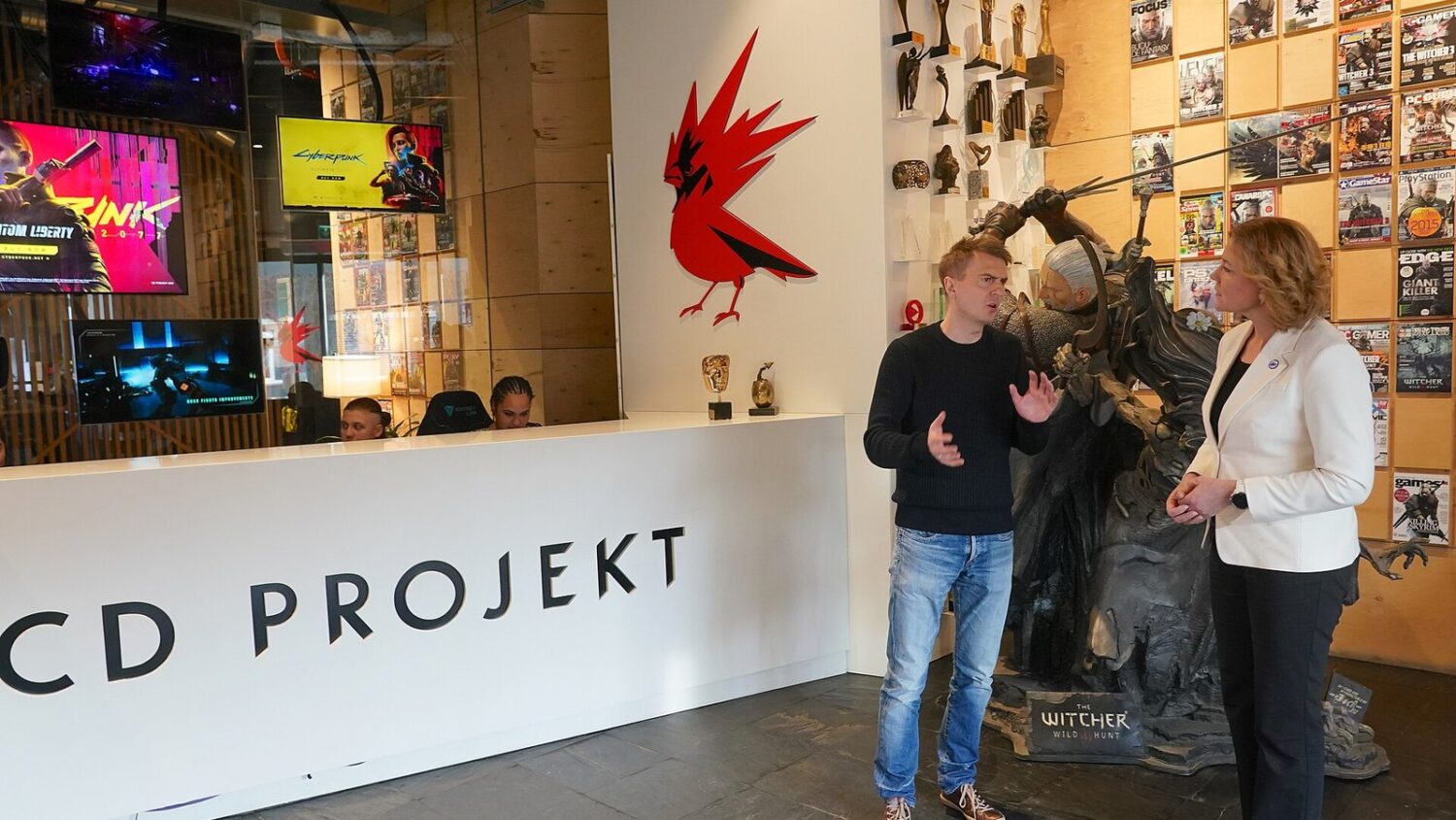 Michał Nowakowski, współzałożyciel i joint CEO CD Projektu, rozmawia z Henną Virkkunen w siedzibie firmy, obok figury…